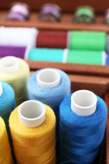 Colorful threads for needlework in wooden box close up