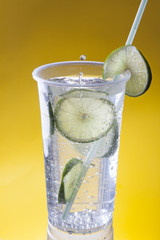Mineral Water With Llime in a Plastic Cup on a Yellow Background