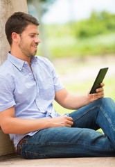 Young man reading E-book outside