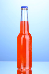 Tasty red drink in bottle on blue background