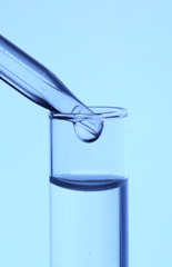 Dropper and test tube, close up, on blue background