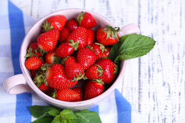 Ripe sweet strawberries in pot and mug