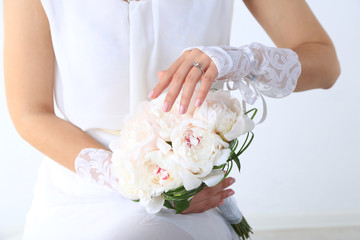 Bride holding wedding bouquet of white peonies, close-up