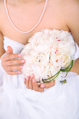 Bride holding wedding bouquet of white peonies, close-up,