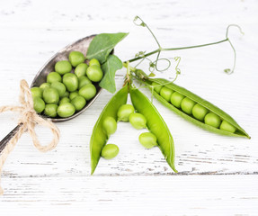 Fresh green peas in spoon on wooden table