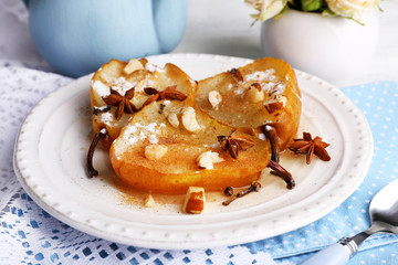 Baked pears with syrup on plate, on bright background