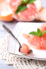Ripe peeled grapefruits on plate, on color wooden background