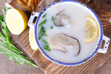 Tasty soup with oysters on wooden table