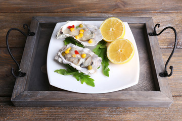 Tasty cooked oysters in shell on wooden table