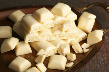 White broken chocolate bar on tray, on color wooden background