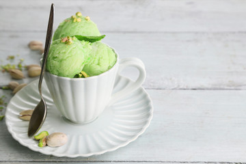 Tasty pistachio ice cream in cup on wooden table