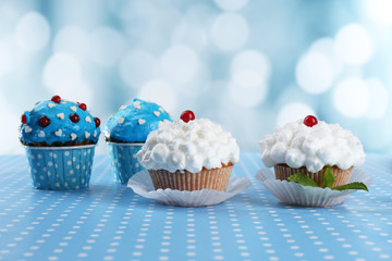 Tasty cupcakes on table, on bright background