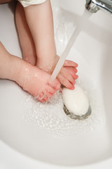 child washes hands and feet in a wash basin