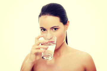 Beautiful young woman drinks clear mineral water