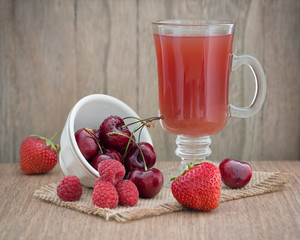 Red fruit drink with fresh red fruits on an old wooden table