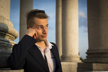 Handsome blond young man with marble columns behind him