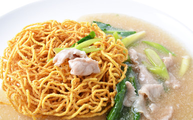 Noodle with pork and kale topping served in white bowl