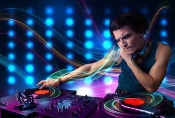 Young Dj mixing records with colorful lights