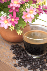 Hot coffee and coffee beans with flower clay pot.