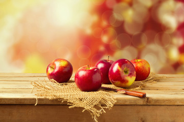 Apples on wooden table over autumn bokeh background
