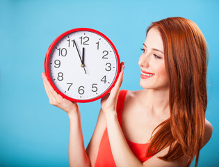 Redhead girl with huge clock on blue background.