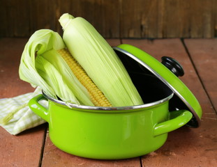 ripe yellow corn and green pan on a wooden background © Olga Kriger