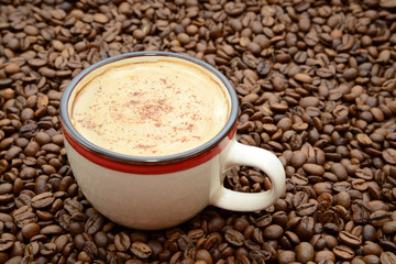 cup of coffee with cinnamon on a coffee beans background