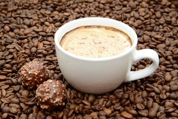 cup of coffee and candies on a coffee beans background