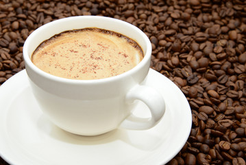 cup of coffee with cinnamon on a coffee beans background