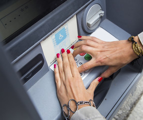 woman with polished nails withdrawing money at atm