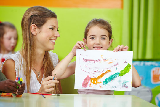 Girl showing self drawn painting in kindergarten