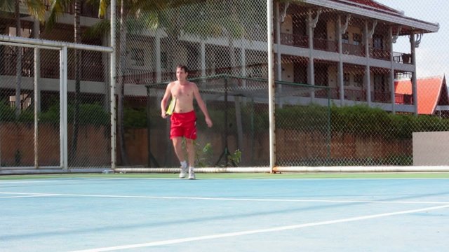 Handosme man with an open-chested playing tennis at the court on