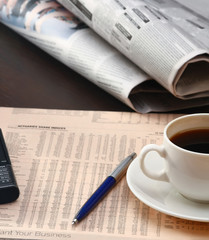 cup of coffee near the laptop and newspapers