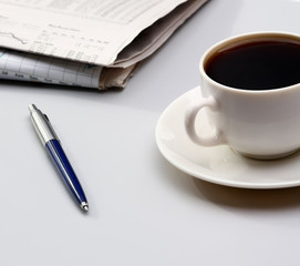 cup of coffee near the laptop and newspapers