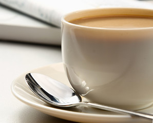 cup of coffee near the laptop and newspapers