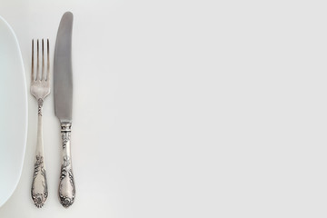 Vintage fork and knife near the plate. Overhead view.