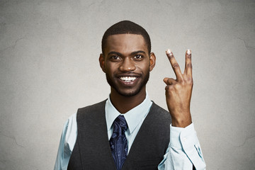Businessman giving victory two fingers sign grey wall background