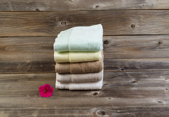 Obraz na płótnie Canvas Clean Towels and single pink flower on Weathered Wood