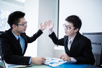 Two Businessmen Having Informal Meeting In Modern Office