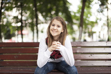 Fashion young woman smiling on a bench