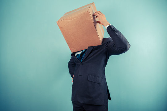 Businessman with box on head is confused