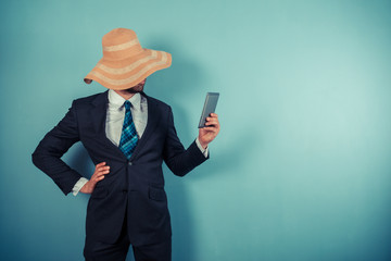 Businessman with beach hat reading on tablet