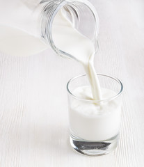 Milk pouring into a glass on white board