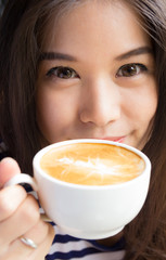 Close up of woman smiling and holding cup of  coffee