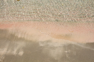 Fototapeta na wymiar Wet fine pink sand washed by sea tide background