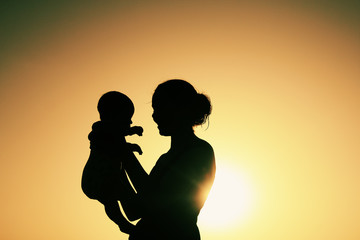 Silhouette of mother and baby at sunset - 66902199