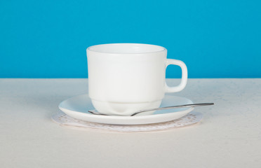 Cup, saucer and spoon on white cloth