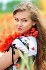 Beautiful young woman in red bright poppy field. Summer portrait