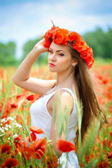 Beautiful young woman in red bright poppy field. Summer portrait