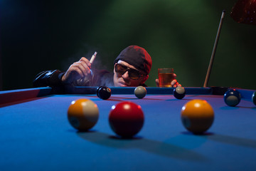 Man playing pool in a club smoking e-cigarette